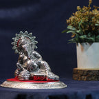 Reclining Ganesha Idol – Silver Finish — Silver tone on a red fabric base