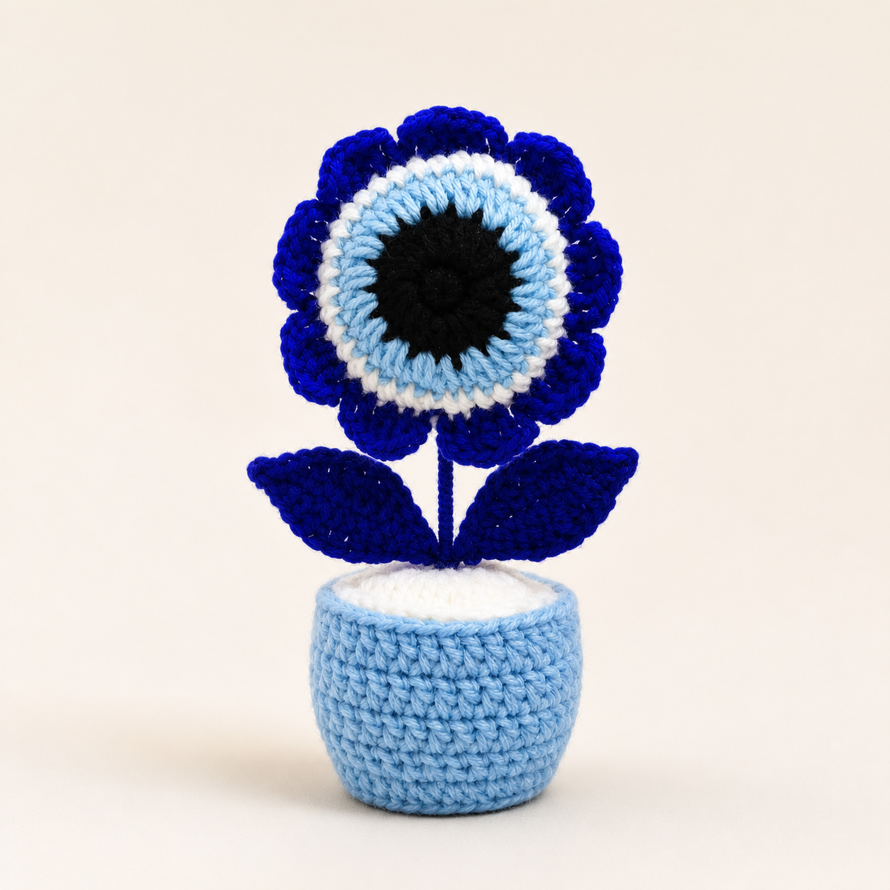 Front view of crochet evil eye flower pot in blue, white and black
