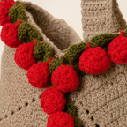 Close-up of red crochet roses, green leaves and detailed stitching