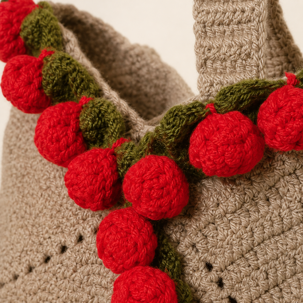Close-up of red crochet roses, green leaves and detailed stitching