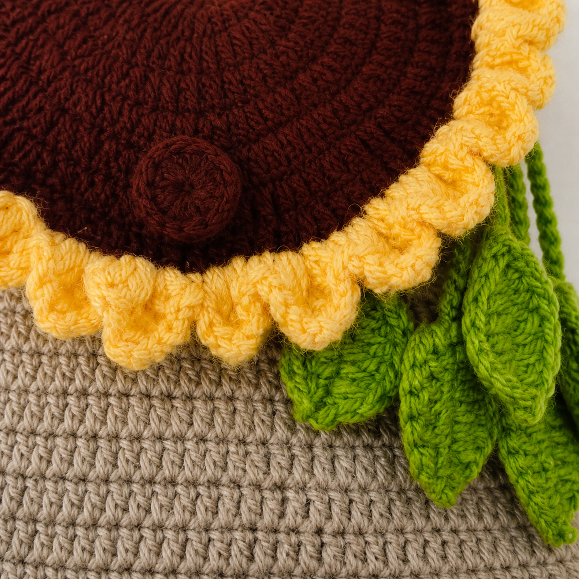 Close-up of crochet sunflower flap, yellow petals and green leaves
