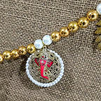 Close-up of pink enamel Ganesha medallion with golden filigree and pearl frame
