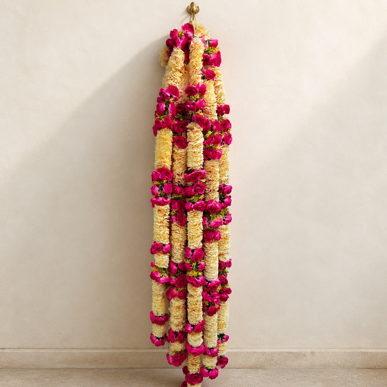6 ft cream and magenta artificial flower garland hanging on a warm ivory wall