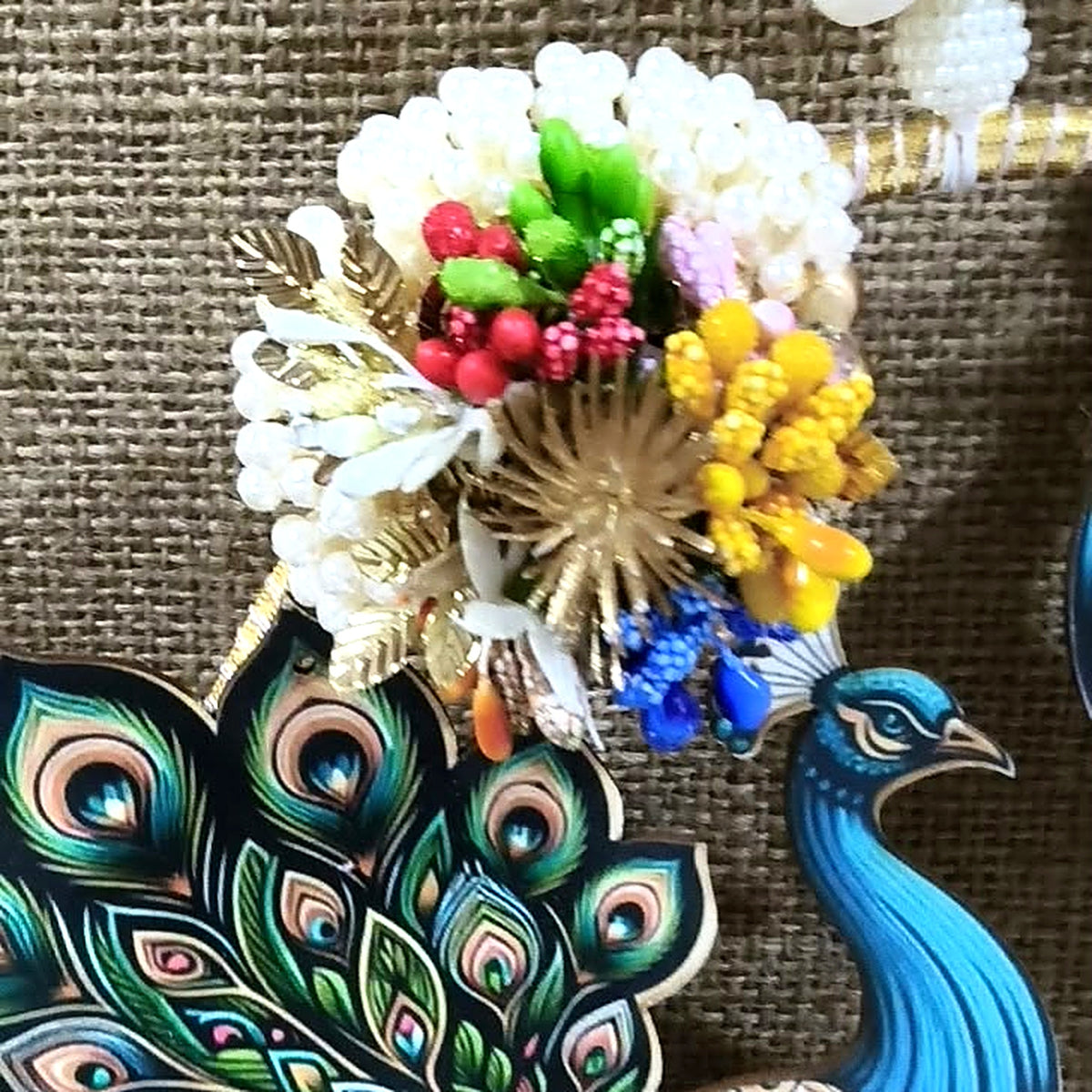 Close-up of pearl and floral cluster on the peacock wall hanging