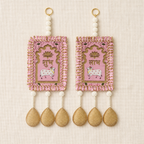 Full view of the pink Shubh Labh door hanging pair on a neutral fabric background