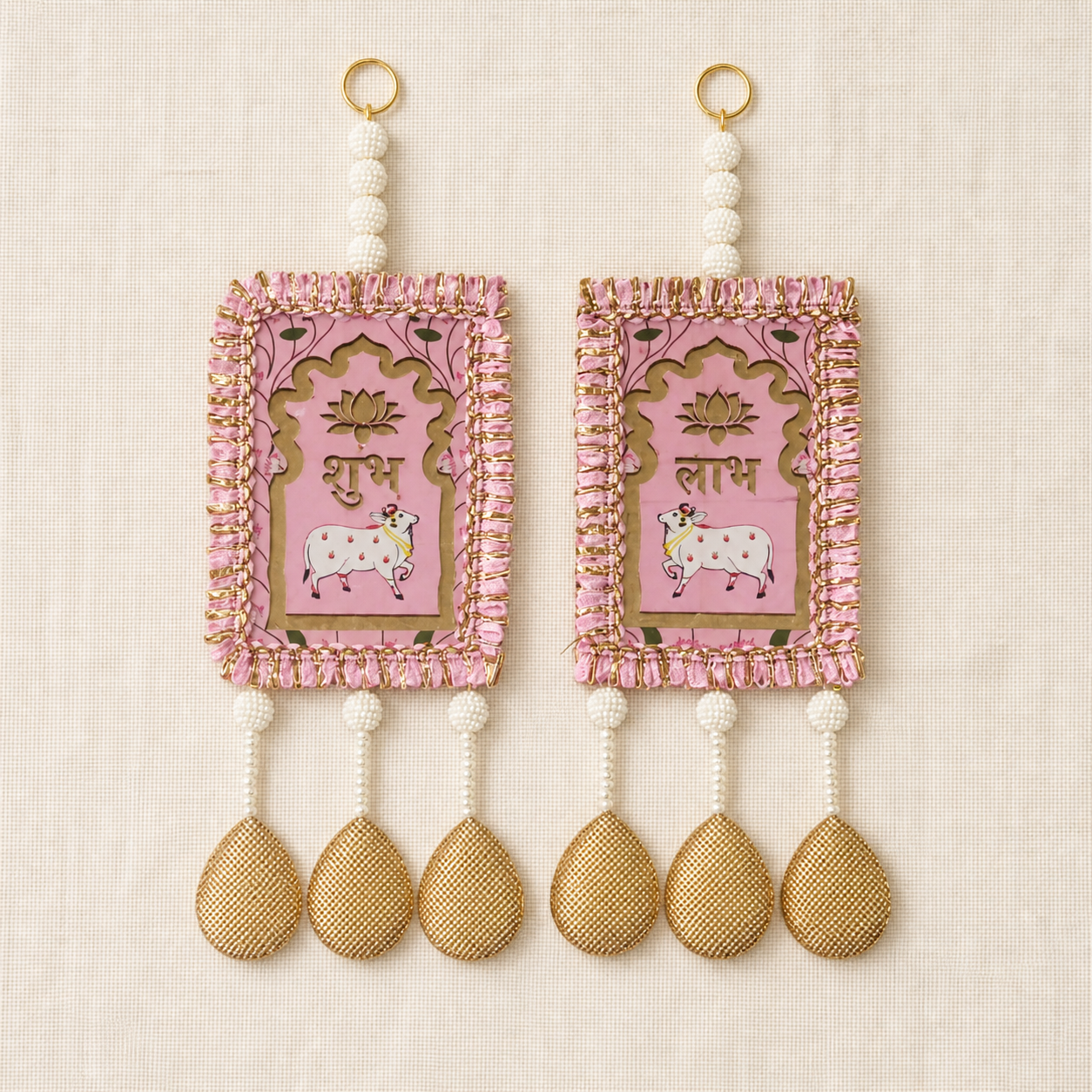 Full view of the pink Shubh Labh door hanging pair on a neutral fabric background
