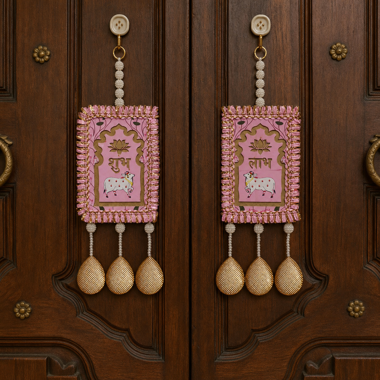 Pink Shubh Labh hanging pair displayed on a carved wooden entrance door
