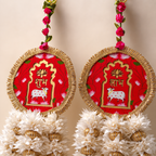 Close-up of round red Shubh and Labh panels with lotus and cow motifs and gold trim